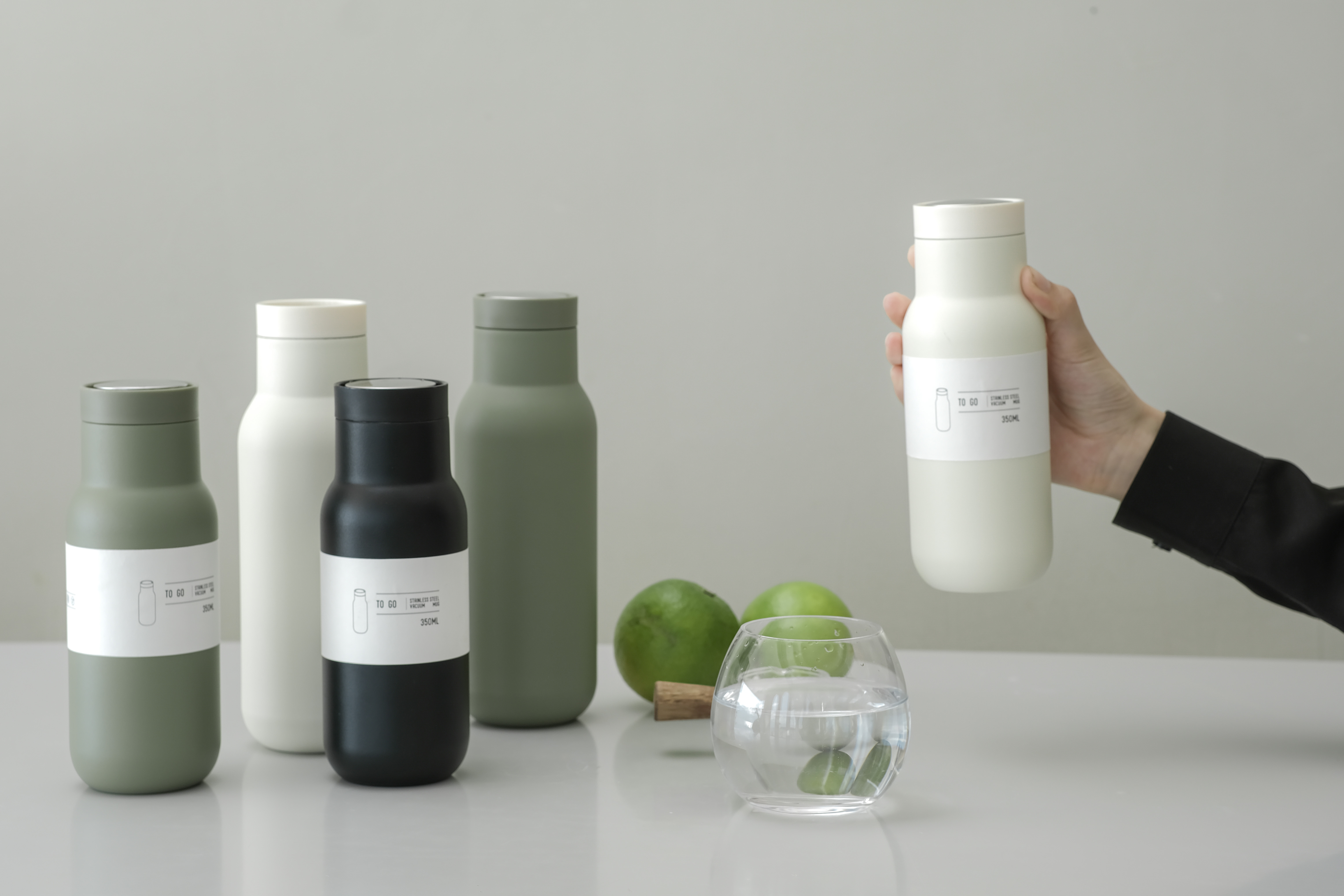 Matte green 350ml stainless steel vacuum bottle on a wooden desk, next to a laptop and a plant, showing compact daily use